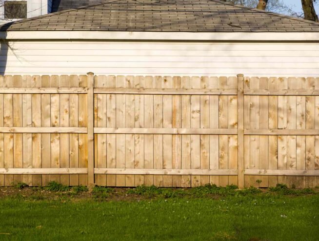 A tall, solid wooden privacy fence installed by Runika.pro in a Miami backyard, providing security and seclusion with a clean, finished look