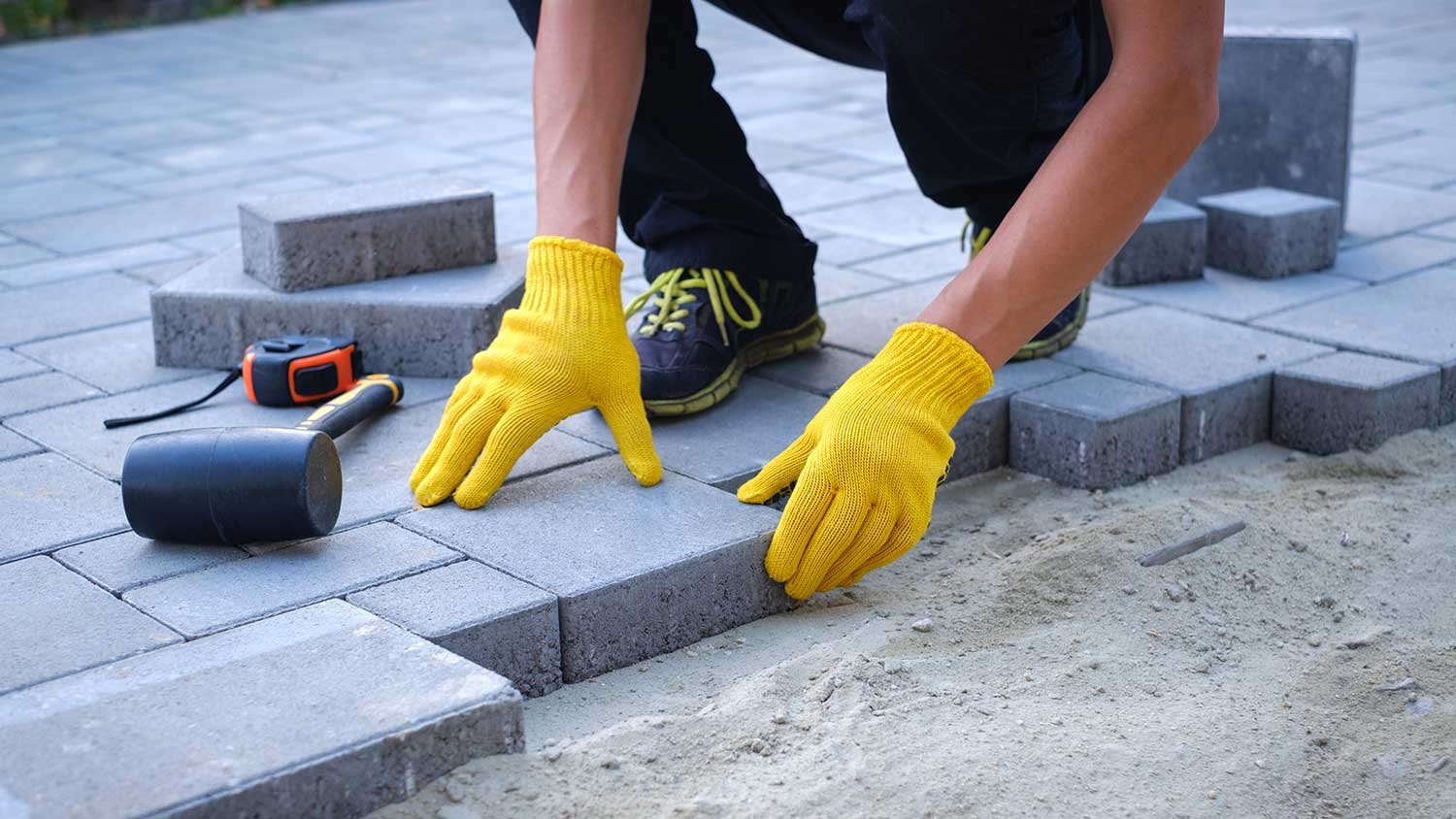 Expert Paver Installation Process in Miami | Precision by Runika.pro Skilled Runika.pro craftsman in Miami meticulously installing interlocking concrete pavers for a durable and level patio foundation