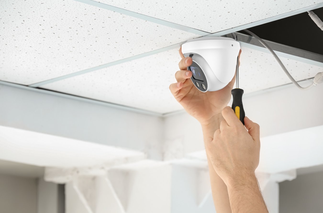 Smart Security Camera Systems Miami | Expert Setup & Remote Access A technician from Runika.pro setting up a modern IP camera system with a networked video recorder (NVR) and smartphone integration for a Miami residence